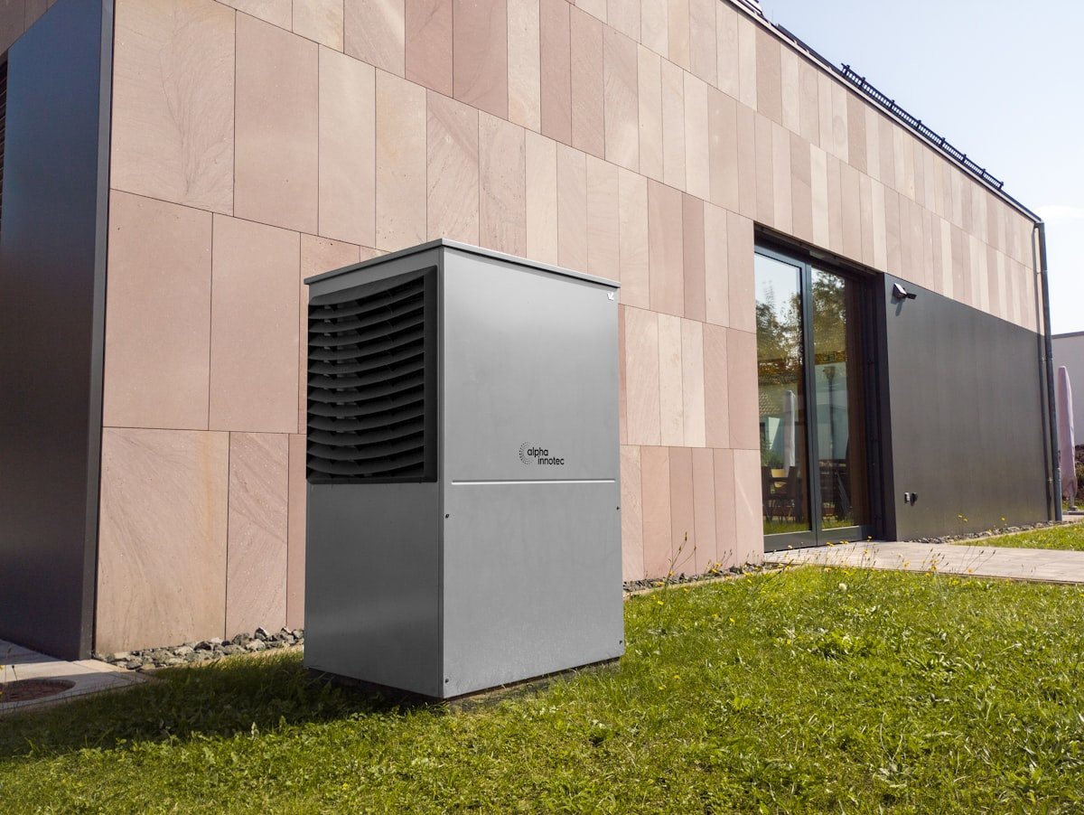 Luft-Wärmepumpe als Außengerät neben einem modernen Wohnhaus